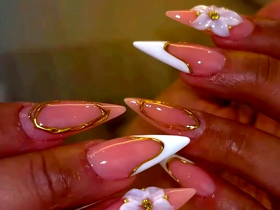 Long stiletto Gel X nails in nude pink with white tips, gold outlines and 3D flower art